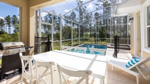 Un espace extérieur abrité comprenant une piscine, un barbecue et des sièges.