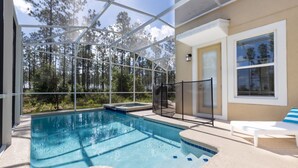 Une piscine dotée d’une structure en verre, entourée d’une terrasse et d’un espace de détente.
