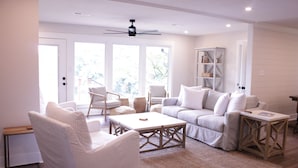 A spacious living room with a white sofa set, a coffee table, and a bookshelf.