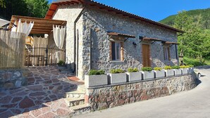 A stone house with a tiled roof, a wooden porch, and a stone wall. - 3 Bedroom Village House with Private Pool in Garfagnana - restaurant nearby (Comune di Villa Collemandina)
