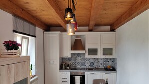 A modern kitchen with white cabinets, a patterned backsplash, and a wooden ceiling. - 3 Bedroom Village House with Private Pool in Garfagnana - restaurant nearby (Comune di Villa Collemandina)