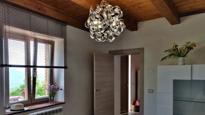 A modern interior with a wooden ceiling, a radiator, a window with blinds, a door leading to another room, and a white cabinet with a plant. - 3 Bedroom Village House with Private Pool in Garfagnana - restaurant nearby (Comune di Villa Collemandina)