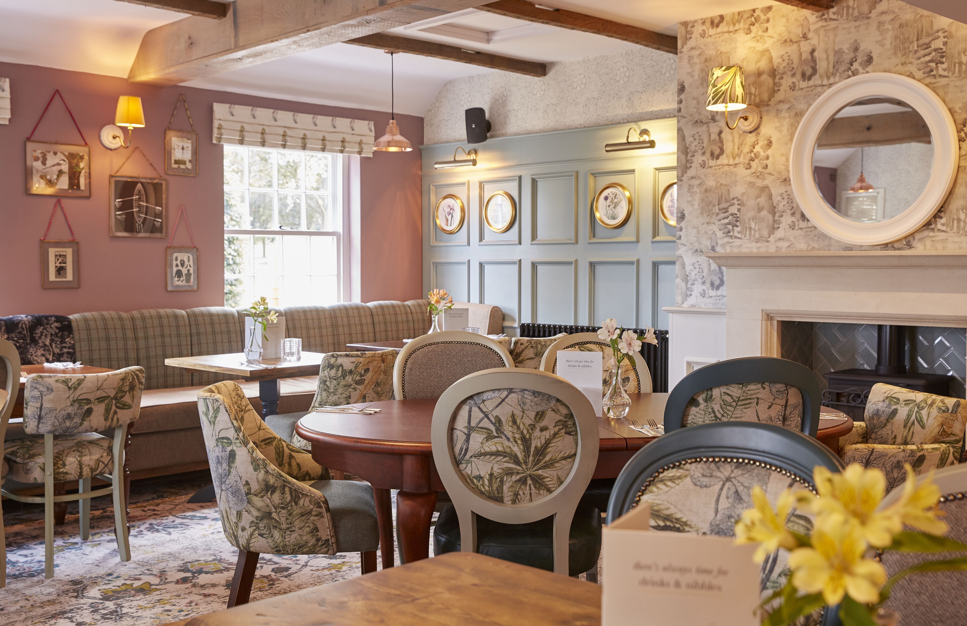 A cozy dining area with wooden tables and chairs, a sofa, and wall-mounted picture frames.