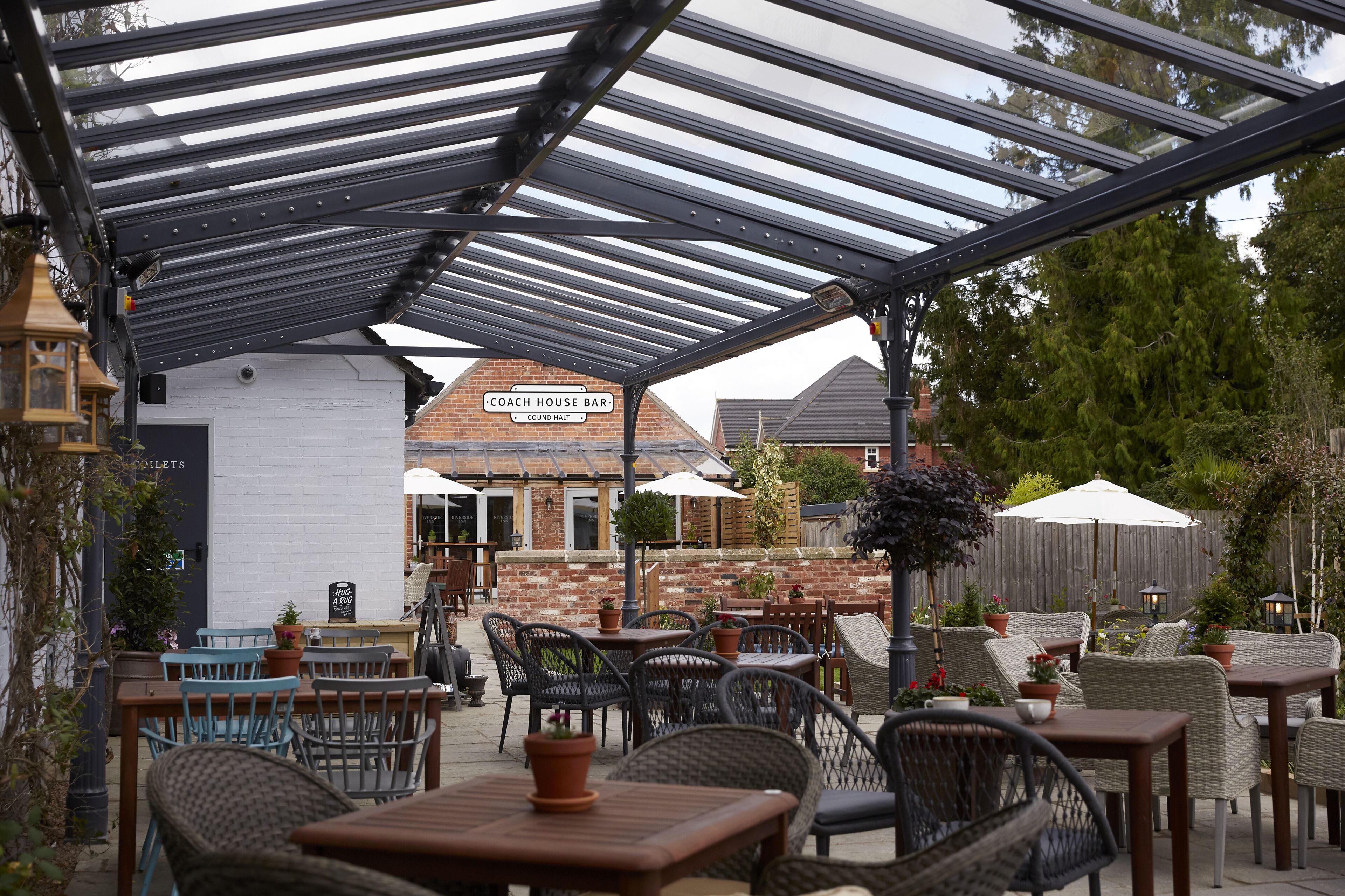 An outdoor patio area with tables and chairs, a covered seating area, and a building labeled "Coach House Bar" in the background.