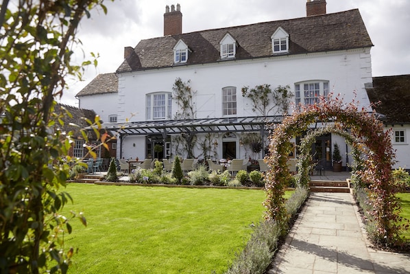 A white building with a garden and outdoor seating area.