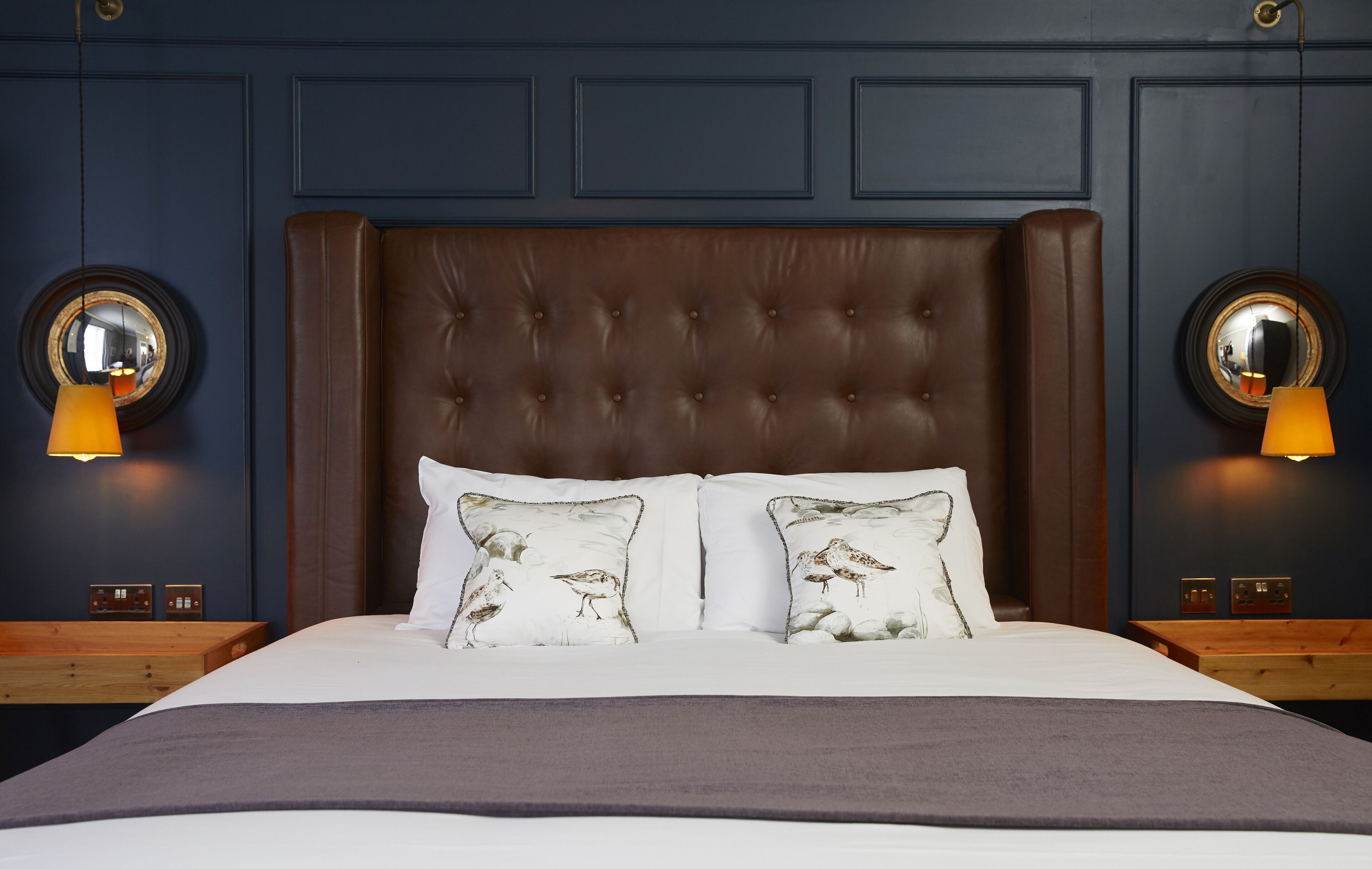 A bed with a tufted headboard, two bedside tables, and two wall-mounted lamps.