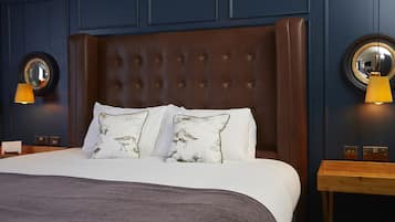 A neatly made bed with two pillows, a wooden nightstand with a lamp, and a wall-mounted mirror.