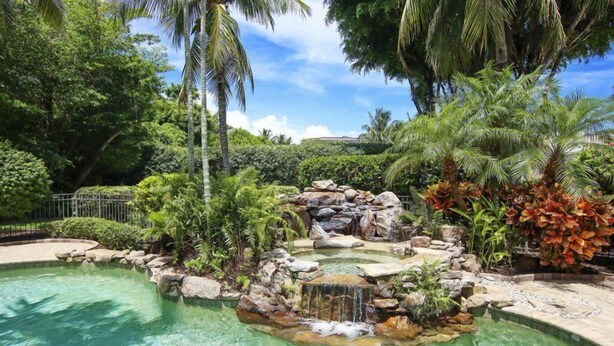 Una piscina con cascada rodeada de follaje tropical.