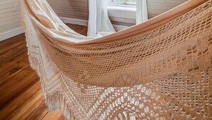 Un hamac dans une pièce dont le sol est en bois et qui possède une fenêtre.