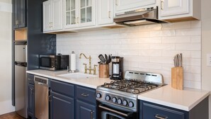 A modern kitchen with white cabinets, a stainless steel stove, and a dishwasher. - Southern Luxury Apartment | Downtown Charlottesville | 30 Night Minimum (Charlottesville)