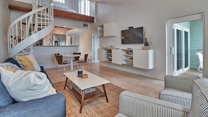 Een ruime woonkamer met een wenteltrap, een eethoek en een keuken.