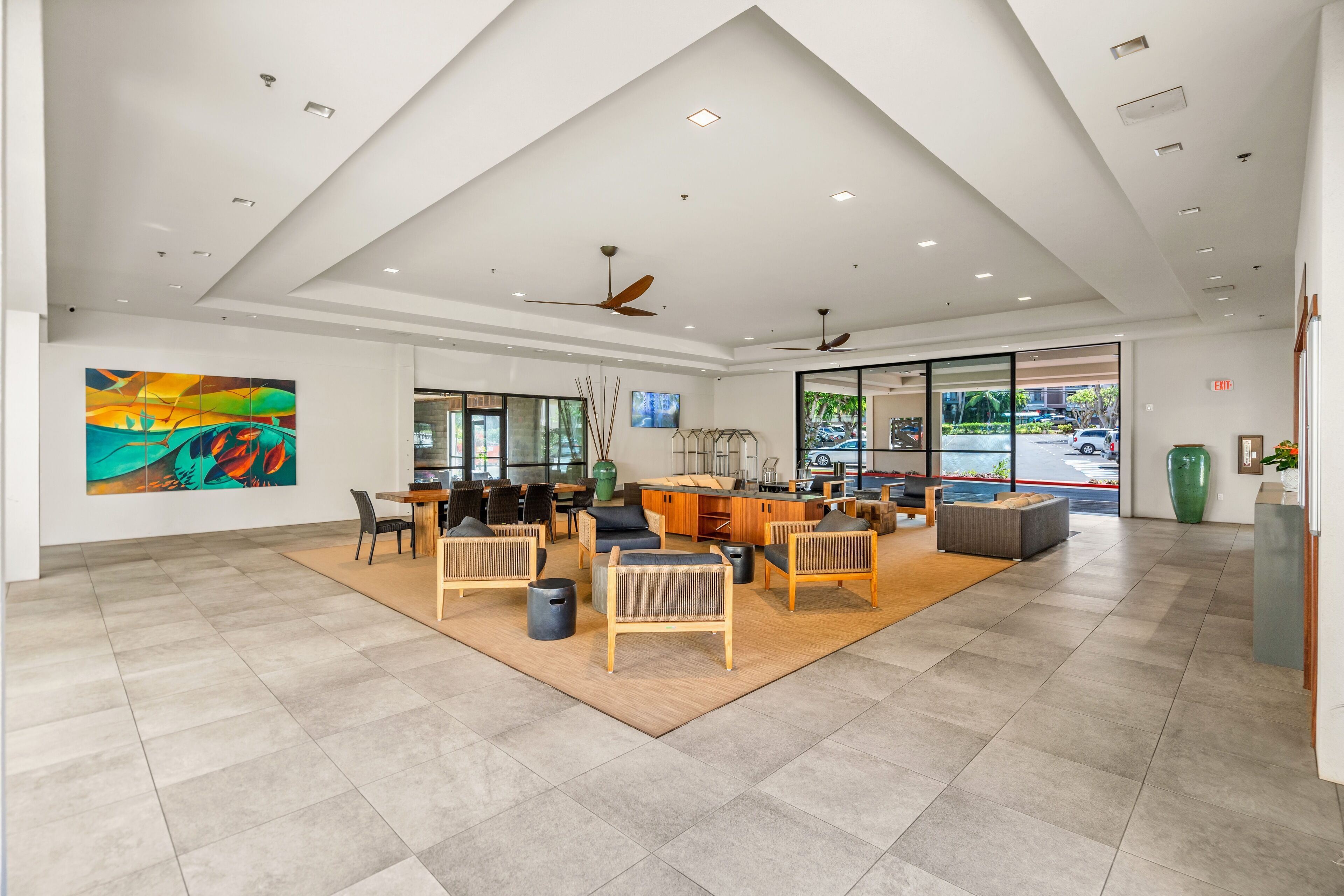 Een ruime lobby met een modern design, met een groot zitgedeelte, een keukenhoek en grote ramen met uitzicht op buiten.