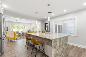 A modern kitchen with a large island, bar stools, and pendant lighting. - Experience the Vibrant Downtown St Pete! (St. Petersburg)