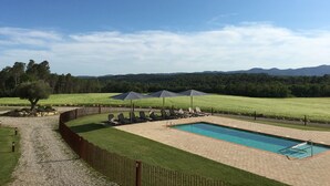 Ein rechteckiger Pool mit Holzterrasse, umgeben von Holzlattenzaun und Rasenfläche.