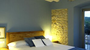 Ein Schlafzimmer mit Bett, Holz-Kopfstück, Wandverkleidung aus Stein und Deckenventilator.