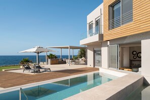A modern house with a pool, outdoor seating, and a view of the sea. - Your Private Retreat by the beach, with Heated Pool (Petres, Rethymno)