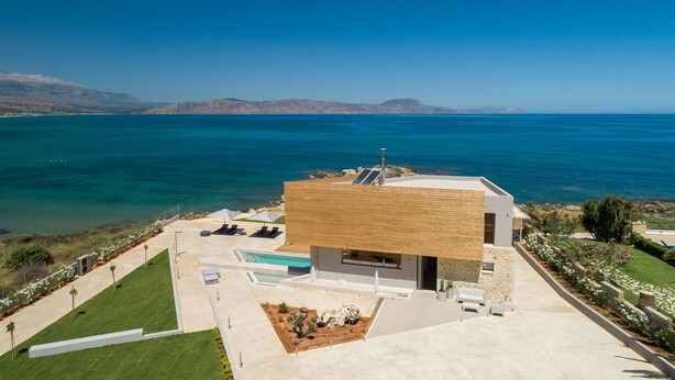 Een modern huis met een zwembad, een tuin en uitzicht op de oceaan.