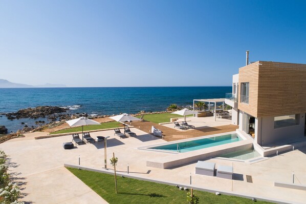 A modern house with a pool, outdoor seating, and a view of the sea. - Your Private Retreat by the beach, with Heated Pool (Petres, Rethymno)