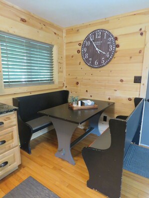 Relax in this inviting room with a comfortable bench, a table, and a window with blinds.