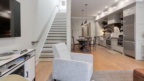 Eine moderne Küche mit Edelstahlgeräten, eine Essecke mit rundem Tisch und Stühlen sowie eine Treppe zu einer weiteren Ebene.