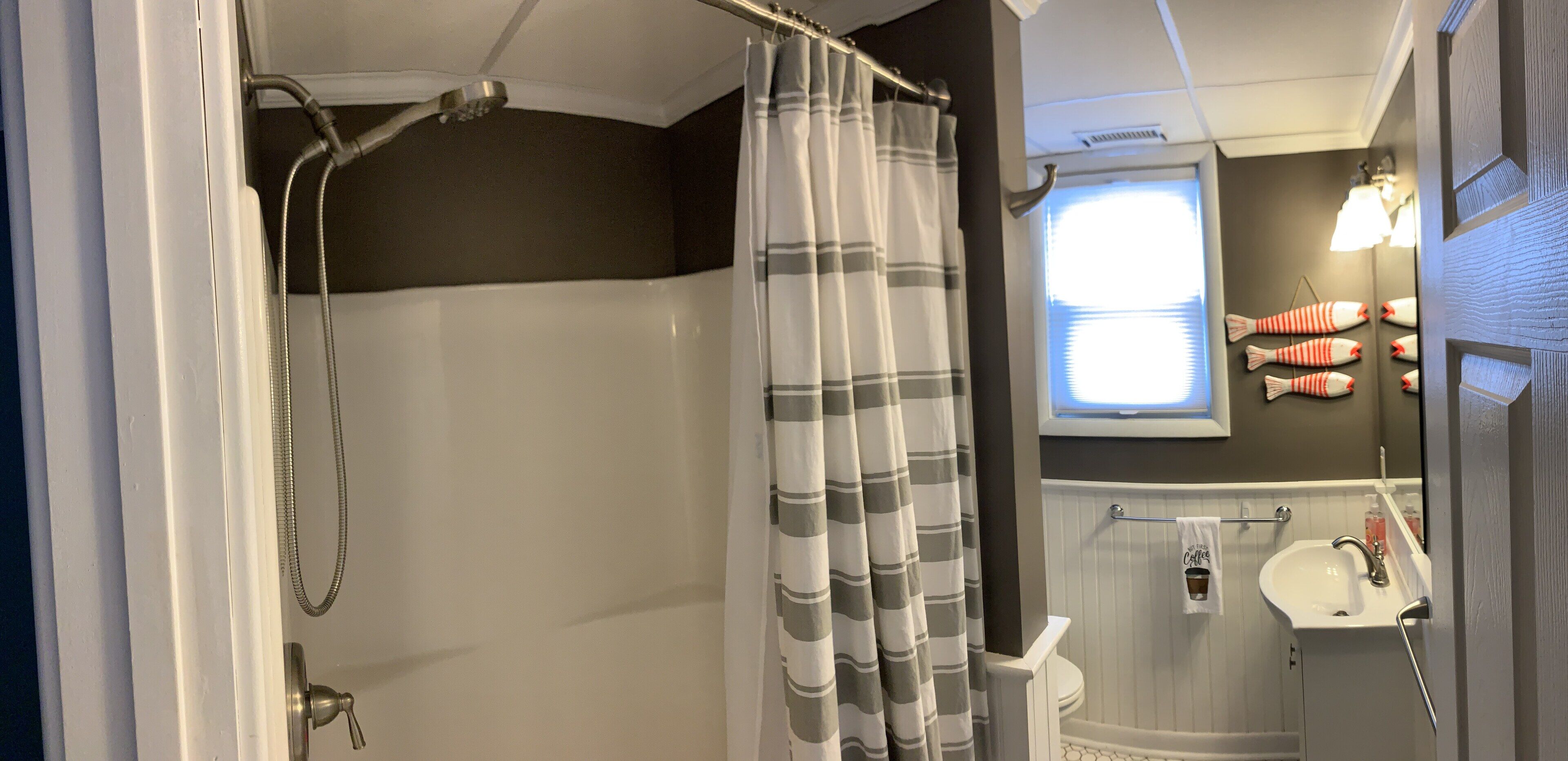Een badkamer met een douche, een raam en een wastafel.