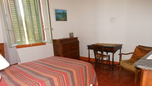 A bedroom with a bed, a wooden dresser, a desk with a chair, and a window with shutters. - Maison de Vacances Gard/cevennes (Cardet)