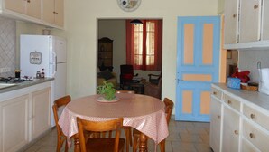 A kitchen with a dining table, chairs, a refrigerator, and a clock on the wall. - Maison de Vacances Gard/cevennes (Cardet)
