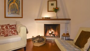 A cozy living room with a fireplace, two sofas, a framed artwork, and a small table with a vase. - Beautiful House With Fantastic Views of the Sierra (Grazalema)