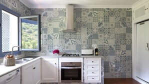A kitchen with patterned tiles, a built-in oven, a window with a view, and a basket of eggs. - Beautiful House With Fantastic Views of the Sierra (Grazalema)