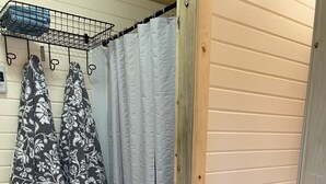 A small bathroom with a shower, a toilet, and a wooden shelf. - Tiny House in the country, close to Billings (Worden)