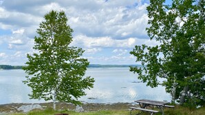 A lakeside picnic area with a bench and a fire pit. - Island View Hotel Bar Harbor (Trenton)