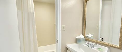 A bathroom with a shower, toilet, sink, and mirror.