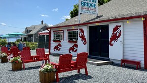 A waterfront restaurant with red chairs and lobster-themed decor. - Island View Hotel Bar Harbor (Trenton)