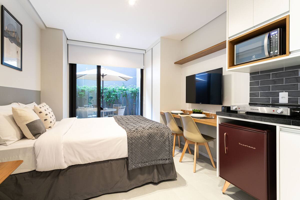 Une chambre d’hôtel moderne équipée d’un lit, d’un bureau et d’une kitchenette.