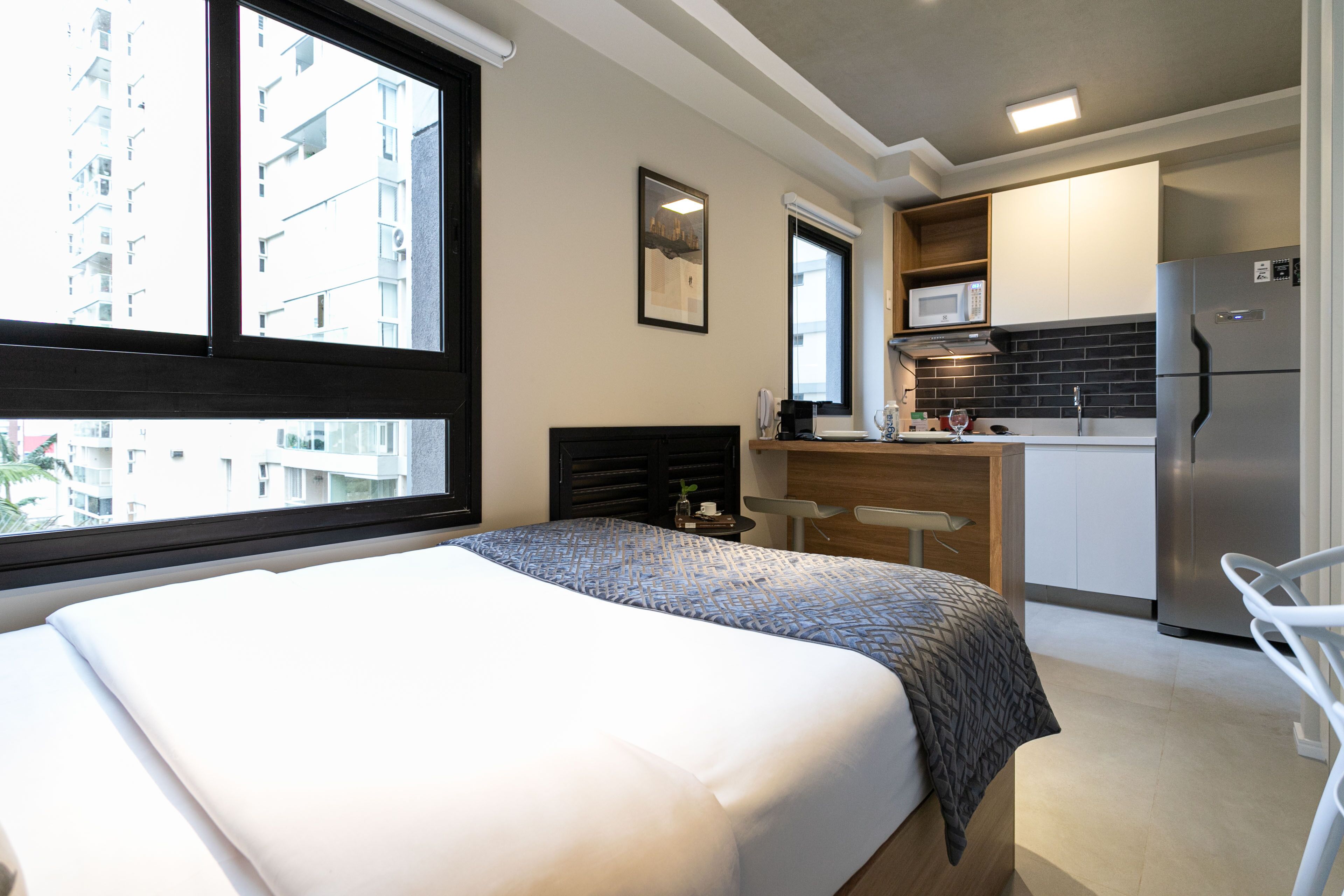 Une chambre d’hôtel avec un lit, une petite kitchenette, un coin repas et une vue sur la ville.