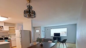 A modern kitchen with white cabinets, a refrigerator, and a dining area with a table and chairs.