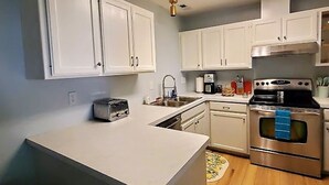 A compact kitchen with white cabinets, a stainless steel oven, and a toaster.