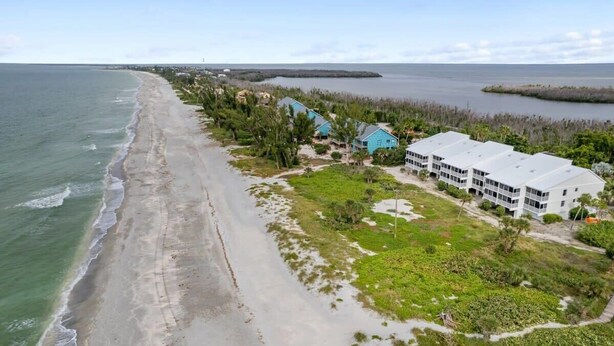 Un hotel frente al mar con vistas a la playa, edificios de varios pisos y una zona ajardinada con senderos.