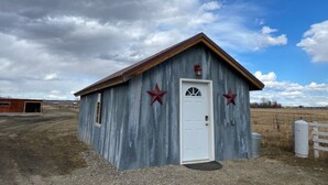 Un petit bâtiment rustique avec une porte blanche et deux étoiles rouges peintes sur le mur.