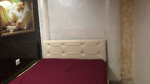 Een slaapkamer met een bed, een schilderij aan de muur en een wit hoofdeinde.