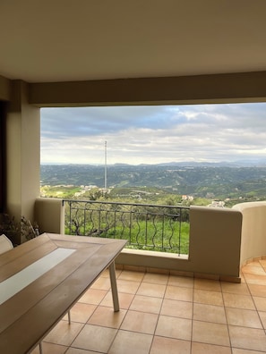 Un balcón con vistas a un paisaje montañoso y una torre distante.