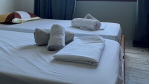 A hotel room with two beds, a large window with curtains, and towels on the beds.