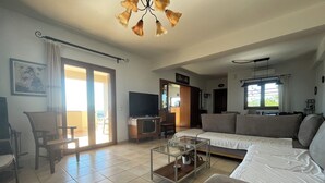 A living room with a sofa, a glass coffee table, a TV, and a dining area with chairs.