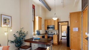 Une cuisine compacte avec des meubles en bois, un îlot central et un luminaire suspendu.