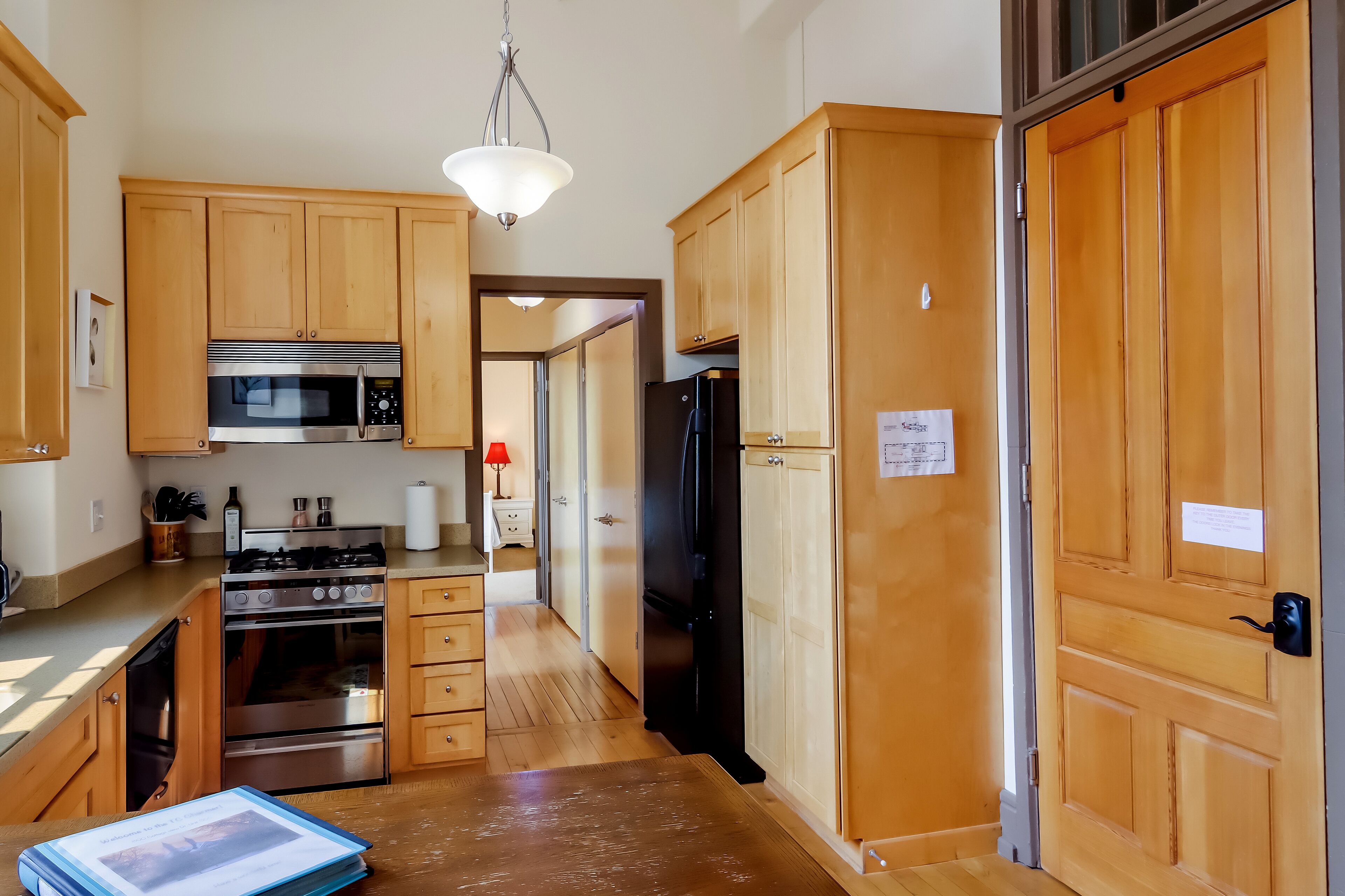 A kitchen with wooden cabinets, a stove, oven, microwave, and refrigerator.