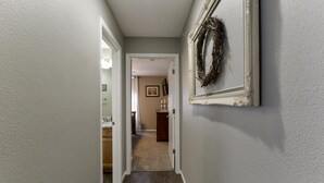 Un corridoio con pavimento in legno, una porta che dà su un bagno e una ghirlanda appesa al muro.