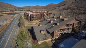 A multi-story hotel with a central courtyard, a parking area, and a view of the surrounding mountains.