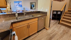 A modern kitchen with granite countertops, stainless steel appliances, wooden cabinets, and a built-in dishwasher.