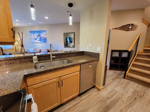 A modern kitchen with granite countertops, stainless steel appliances, wooden cabinets, and a built-in dishwasher.