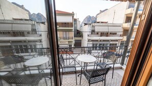 Een balkon met zitplaatsen, uitzicht op gebouwen en een berg op de achtergrond.